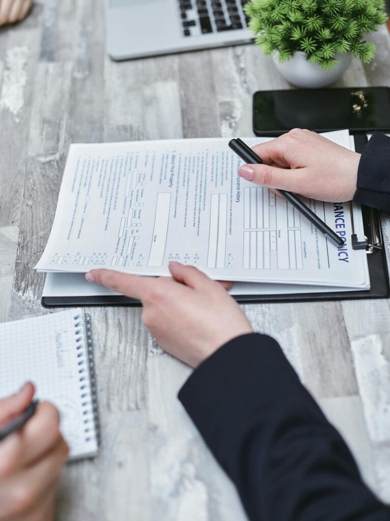 Close-up of hands analyzing insurance policy paperwork with pen on table. Stock Photo