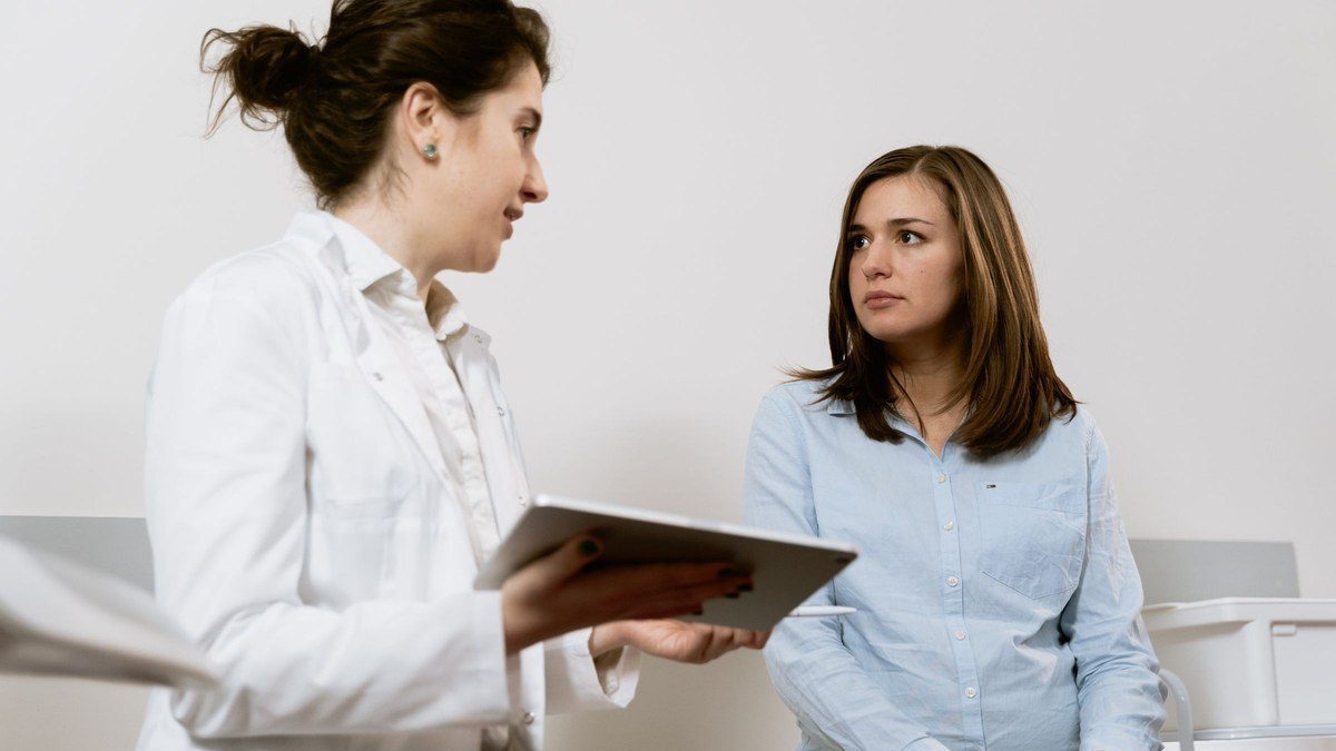 Clinician holding a tablet while talking with a patient in a bright clinic